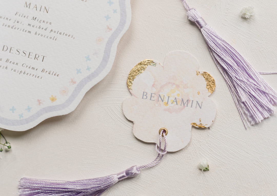 Bespoke flower shape wedding place card with purple tassels on a light background