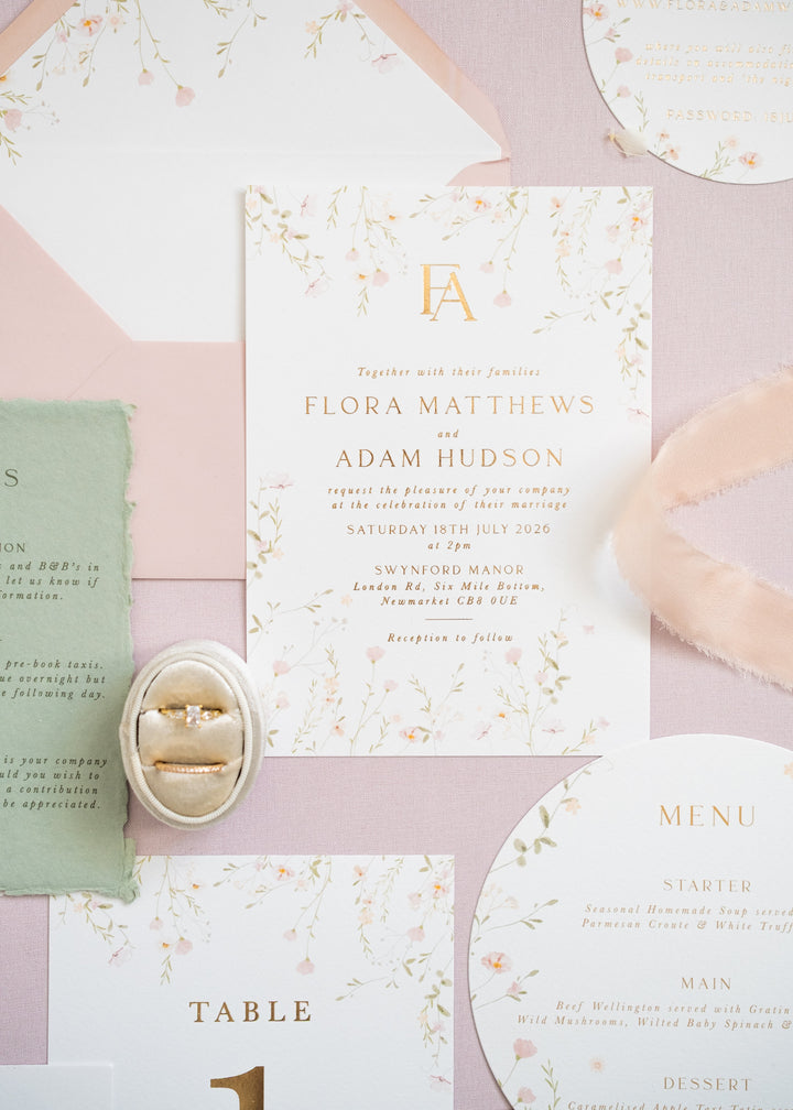 A flat lay of pink floral wedding stationery