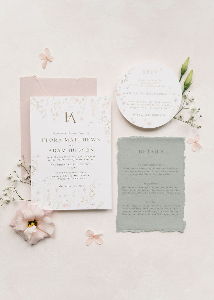 Wedding invitation set with floral decorations on a light pink background