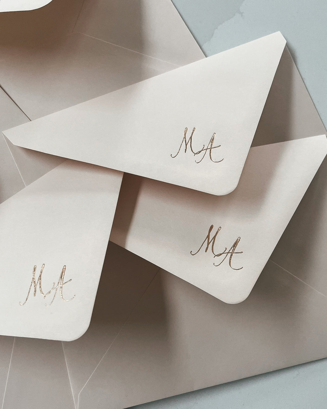Beige envelopes with 'MA' initials on a light gray background