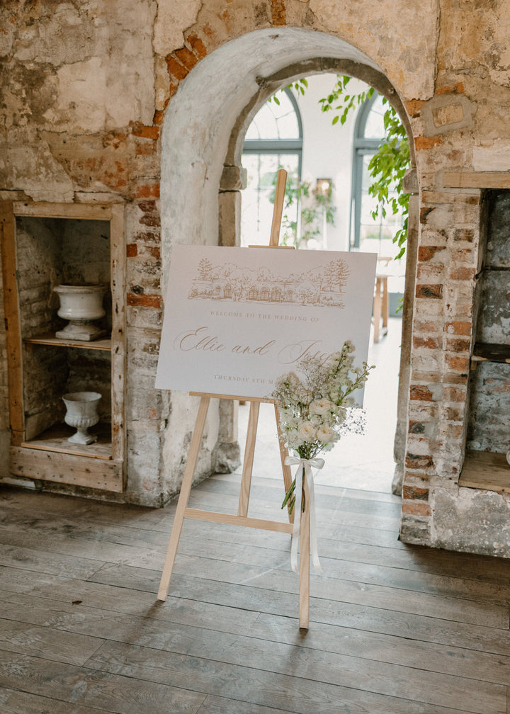 Easel with a wedding sign in a rustic indoor setting with brick walls and wooden floor.