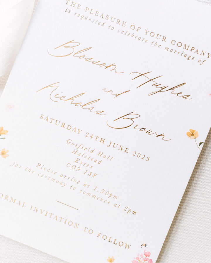 Wedding invitation featuring pressed floral illustrations on a light background