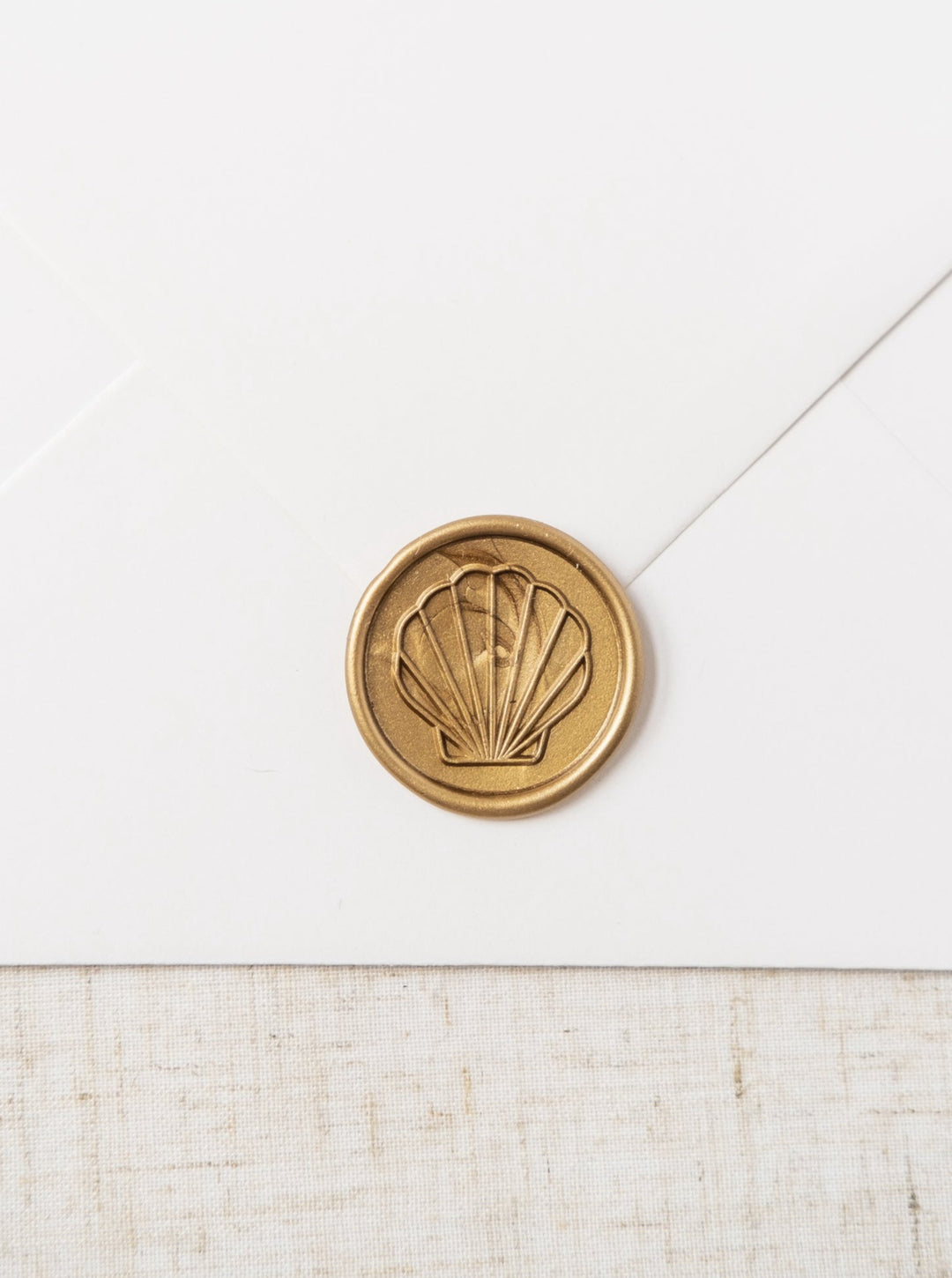 Beautiful gold wax seals featuring a line drawing of a sea shell